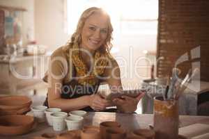 Beautiful female potter using digital tablet