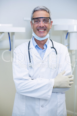 Portrait of smiling dentist standing with arms crossed