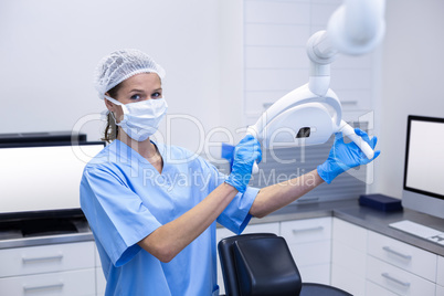 Smiling dental assistant adjusting light