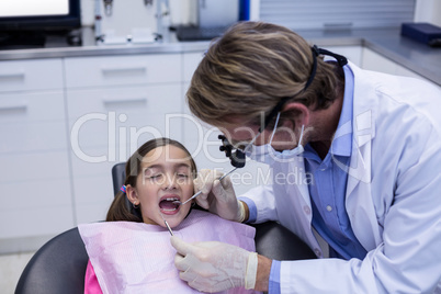 Dentist examining a young patient with tools