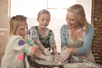 Smiling female potter assisting girls