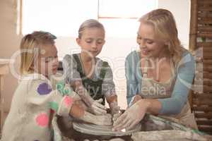 Smiling female potter assisting girls