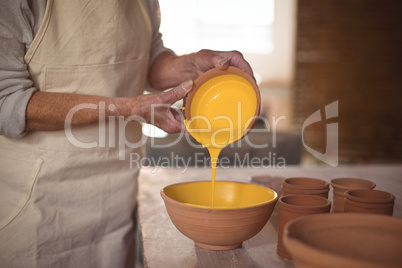 Mid section of female potter pouring watercolor in bowl