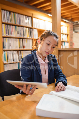 Young woman using digital tablet while studying in library