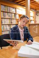 Young woman using digital tablet while studying in library