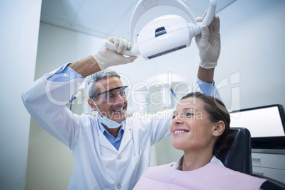 Female dentist adjusting dental light over patient