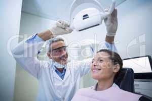 Female dentist adjusting dental light over patient