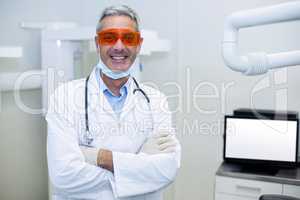 Portrait of smiling dentist standing with arms crossed