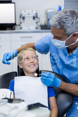 Dentist interacting with young patient while examining