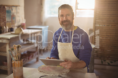 Portrait of male potter using digital tablet