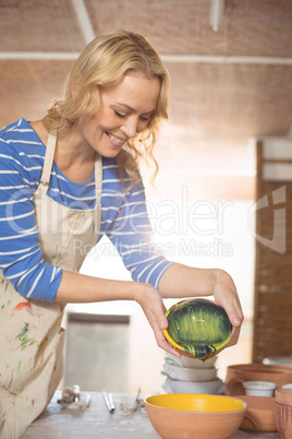 Female potter pouring watercolor in bowl