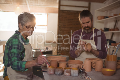 Male and female potter painting pots