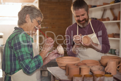 Male and female potter painting pots