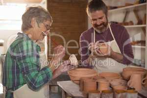 Male and female potter painting pots