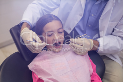 Dentist examining a young patient with tools