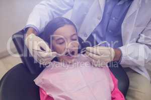 Dentist examining a young patient with tools