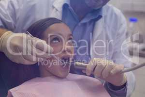 Dentist examining a young patient with tools