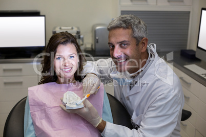 Dentist showing mouth model to female patient