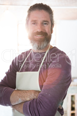 Happy male potter standing in pottery workshop