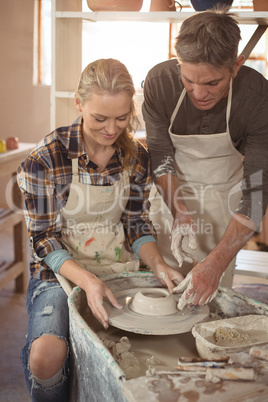 Male potter assisting female potter