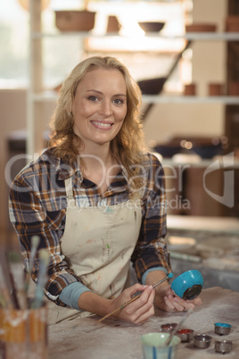 Smiling female potter painting on bowl