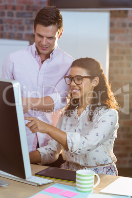 Businesswoman interacting with coworker while working on compute