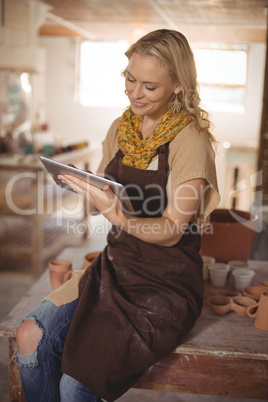 Beautiful female potter using digital tablet