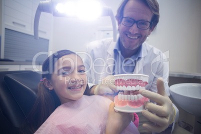 Dentist showing model teeth to patient