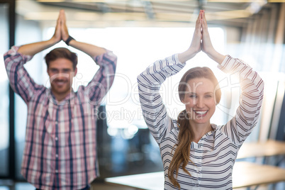 Smiling business people performing yoga in office