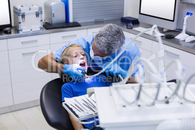 Dentist examining a young patient with tools