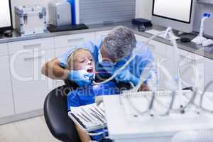 Dentist examining a young patient with tools