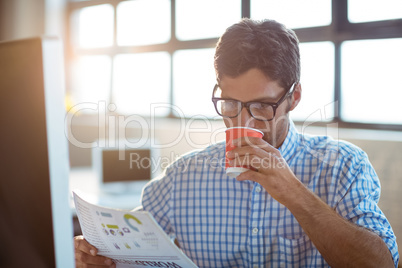 Male business executive reading newspaper while having coffee