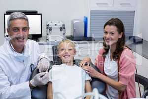 Portrait of dentist with young patient and his mother