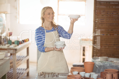 Beautiful female potter checking bowl