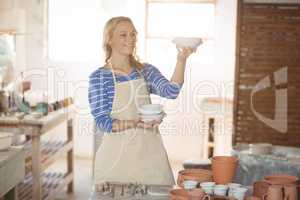 Beautiful female potter checking bowl