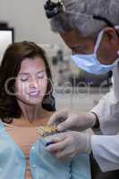 Dentist examining female patient with teeth shades