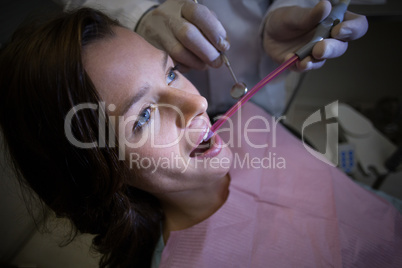 Dentist examining a female patient with tools