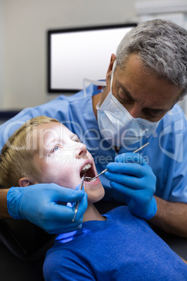 Dentist examining a young patient with tools