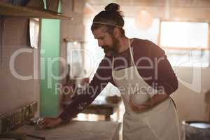 Male potter holding clay and cleaning table