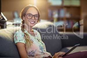 Smiling business executive sitting on sofa and using digital tab