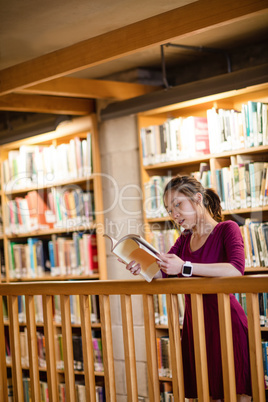 Young woman reading book in library