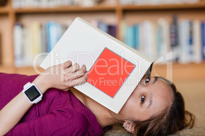 Young woman covering her face with book