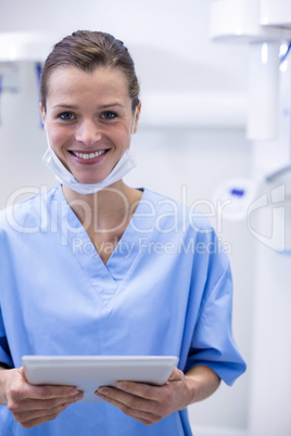 Smiling dental assistant holding digital tablet