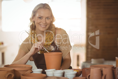 Beautiful female potter painting on pot