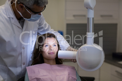 Dentist examining a female patient with dental tool