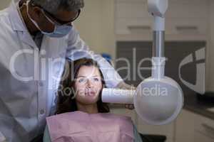 Dentist examining a female patient with dental tool