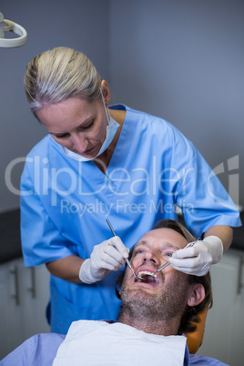 Dentist examining a young patient with tools