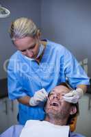 Dentist examining a young patient with tools