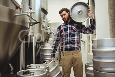 Young manufacturer carrying kegs in brewery