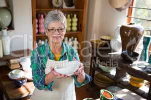 Happy female potter holding bowl